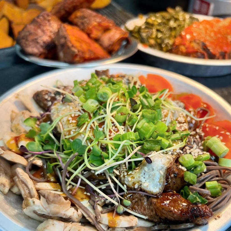 A close-up of a Farm Fresh Fast noodle bowl with meat, mushrooms, and green onions.