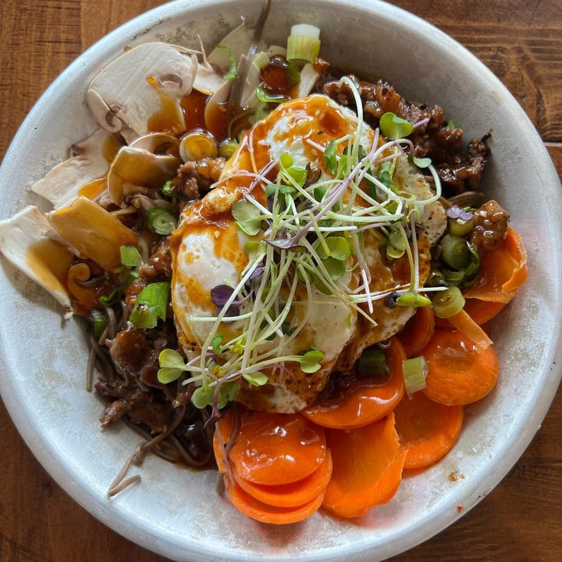 A Farm Fresh Fast bowl with soba noodles, meat, mushrooms, carrots, a fried egg, and sprouts.